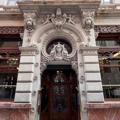 Ornate carved stone doorway of the Real Casino de Murcia on Calle Trapería, with lion heads, a female bust above the arch and a wooden door with stained glass